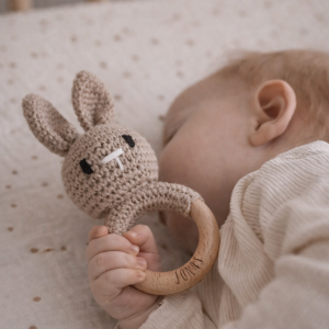 Schlafendes Baby mit einer Rassel in FOrm eines gehäkelten Hasen mit Namensgravur