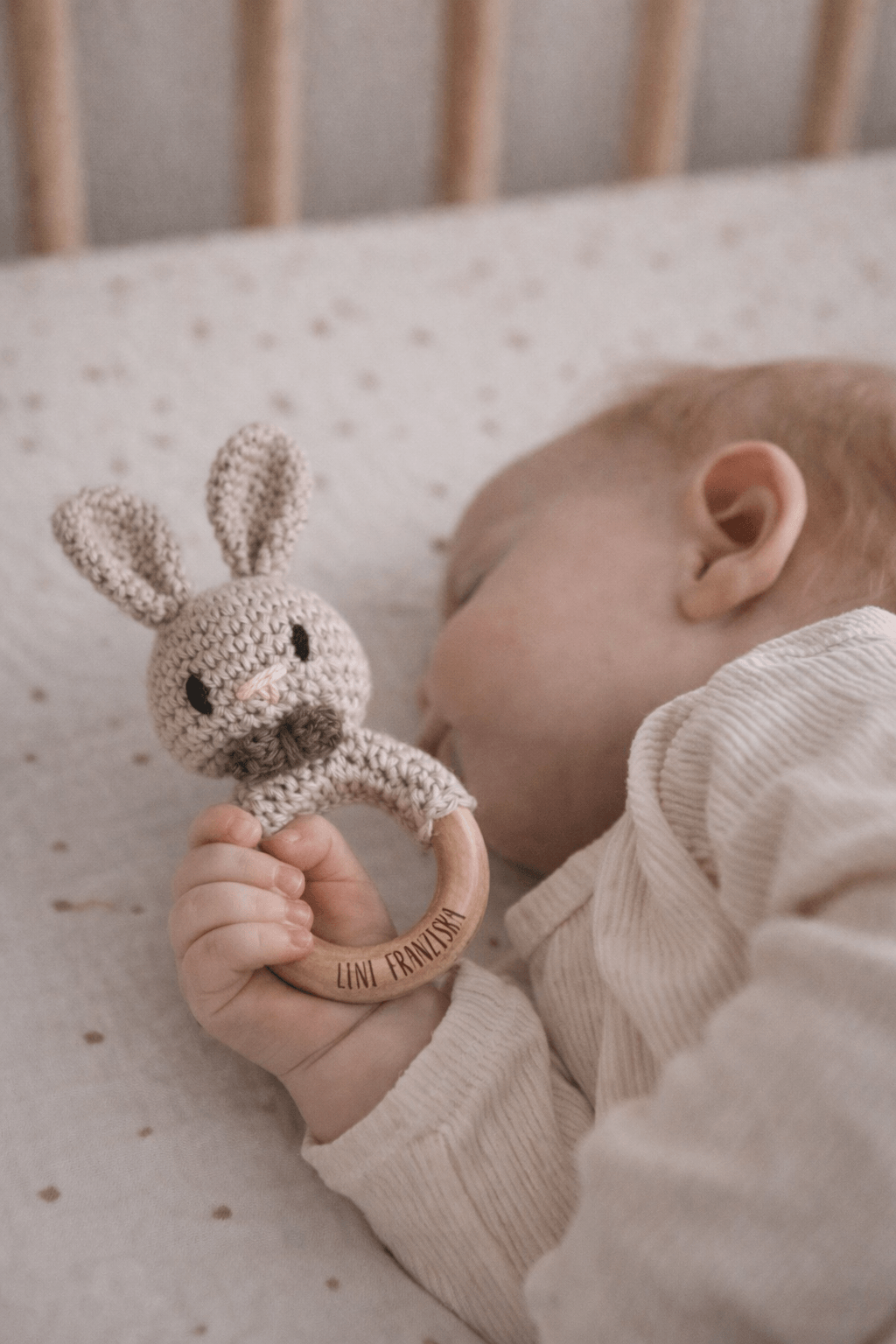 Schlafendes Baby mit einer Rassel in FOrm eines gehäkelten Hasen mit Namensgravur