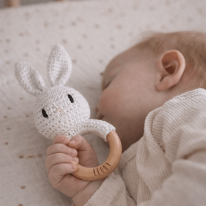 Schlafendes Baby mit einer Rassel in FOrm eines gehäkelten Hasen mit Namensgravur