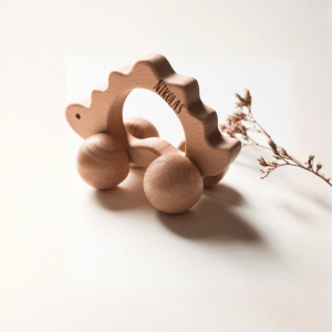 Holzspielzeug in Form eines Dinosauriers mit Rädern mit der Gravur "Nikolas" in einem minimalistischen Hintergrund
