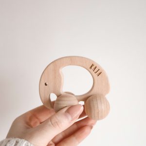 Elefant aus Holz mit Rädern und Namensgravur "Kaja" von einer Hand gehalten vor einem neutralen Hintergrund