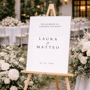 Weißes Willkommensschild mit Text auf einer Staffelei in einer Hochzeitsszenerie