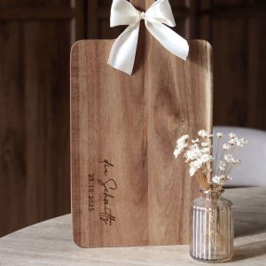 Holzbrett mit weißer Schleife am Griff und Namensgravur auf dem Brett