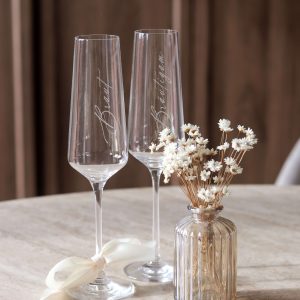 zwei Sektgläser mit Gravur "Braut" und "Bräutigam" und weißer Schleife am Stiel
