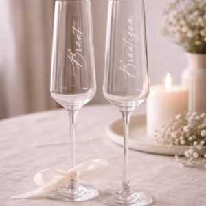 zwei Sektgläser mit Gravur "Braut" und "Bräutigam" und weißer Schleife am Stiel