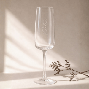 Sektglas mit Gravur "Petra" in einem minimalistischen Hintergrund mit natürlichem Sonnenlicht und zartem Zweig