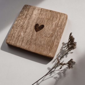 Quadratischer Untersetzer aus Mangoholz mit einem Herz in der Mitte in einem neutralen Hintergrund