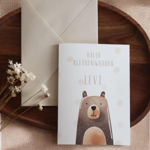 Grußkarte im Postkarten format mit Bärenmotiv und Namen daneben einer beiger Umschlag auf einem Holztablett und Trockenblumen