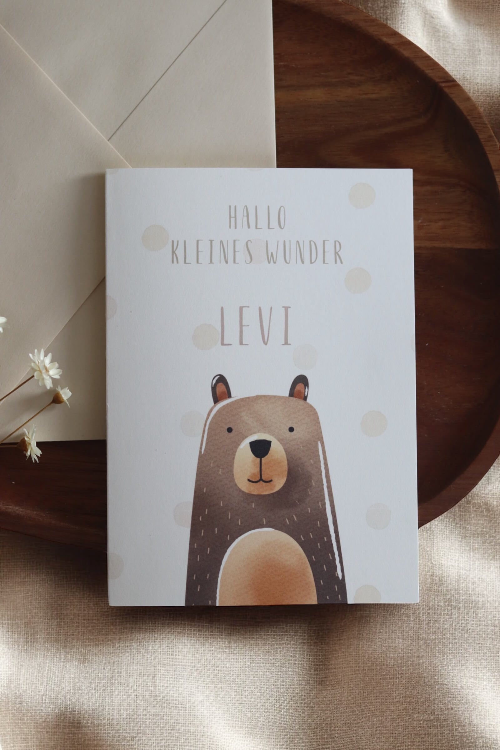 Grußkarte im Postkarten format mit Bärenmotiv und Namen daneben einer beiger Umschlag auf einem Holztablett und Trockenblumen
