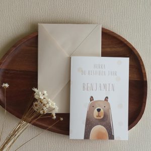 Grußkarte im Postkarten format mit Bärenmotiv und Namen daneben einer beiger Umschlag auf einem Holztablett und Trockenblumen