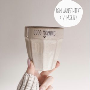 Personalisierter Keramikbecher mit Wunschtext (maximal zwei Worte), minimalistisch gestaltet, in der Hand gehalten vor hellem, neutralem Hintergrund.