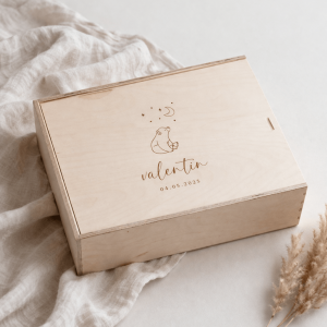 Erinnerungskiste aus hellem Buchenholz mit Schiebedeckel und gravierten Namen und Bärmotiv auf einer hellen Decke