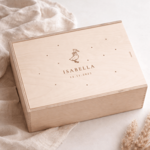 Erinnerungskiste aus hellem Buchenholz mit Schiebedeckel und gravierten Namen und Gansmotiv auf einer hellen Decke