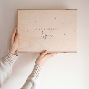 Personalisierte Erinnerungskiste aus Naturholz mit Gravur „Meine Schulzeit Noah", schlichtes Design, wird vor hellem Hintergrund in der Hand gehalten.