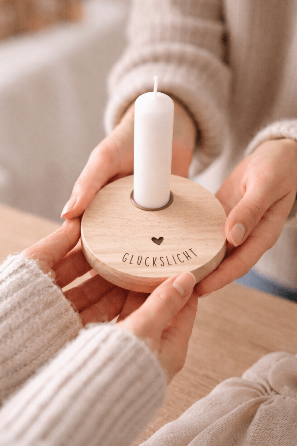 Runde Holzscheibe mit Kerze und der Gravur "Glückslicht" und Herz wird einer anderen Person in die Hände gegeben