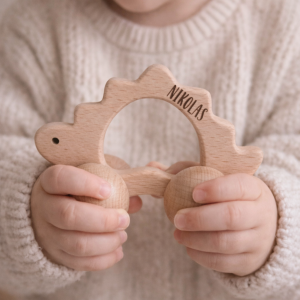 Kleinkind mit personalisiertem Greifling aus Holz in Form eines Dinosauriers