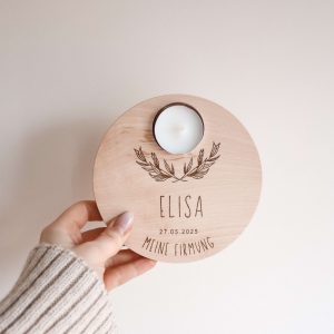 Runder Holzteller aus hellem Buchenholz mit dem Motiv von zwei Zweigen und dem Text "Elisa, meine Firmung", von einer Hand gehalten vor einem neutralen Hintergrund