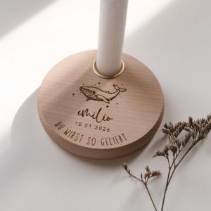 Personalisierter Geburtstagsteller aus Buchenholz mit Wal-Motiv, Name und Datum graviert, mit weißer Kerze, in der Hand gehalten vor hellem Hintergrund.