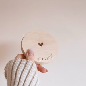 helle runde Holzscheibe mit dem Text "Wunschtext" und einem Herz in der Mitte von einer Hand gehalten vor einem neutralen Hintergrund