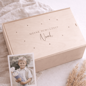 Erinnerungskiste aus hellem Buchenholz mit Schiebedeckel und gravierten Namen und Text "Meine Schulzeit" auf einer hellen Decke und einem Foto mit einem Jungen mit Schultüte