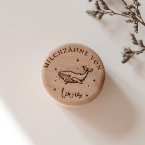Runde helle Holzdose mit einem Namen und einem Wal Motiv vor neutralem Hintergrund