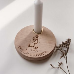 Personalisierter Geburtstagsteller aus Buchenholz mit Hasen-Motiv, Name und Datum graviert, mit weißer Kerze, in der Hand gehalten vor hellem Hintergrund.
