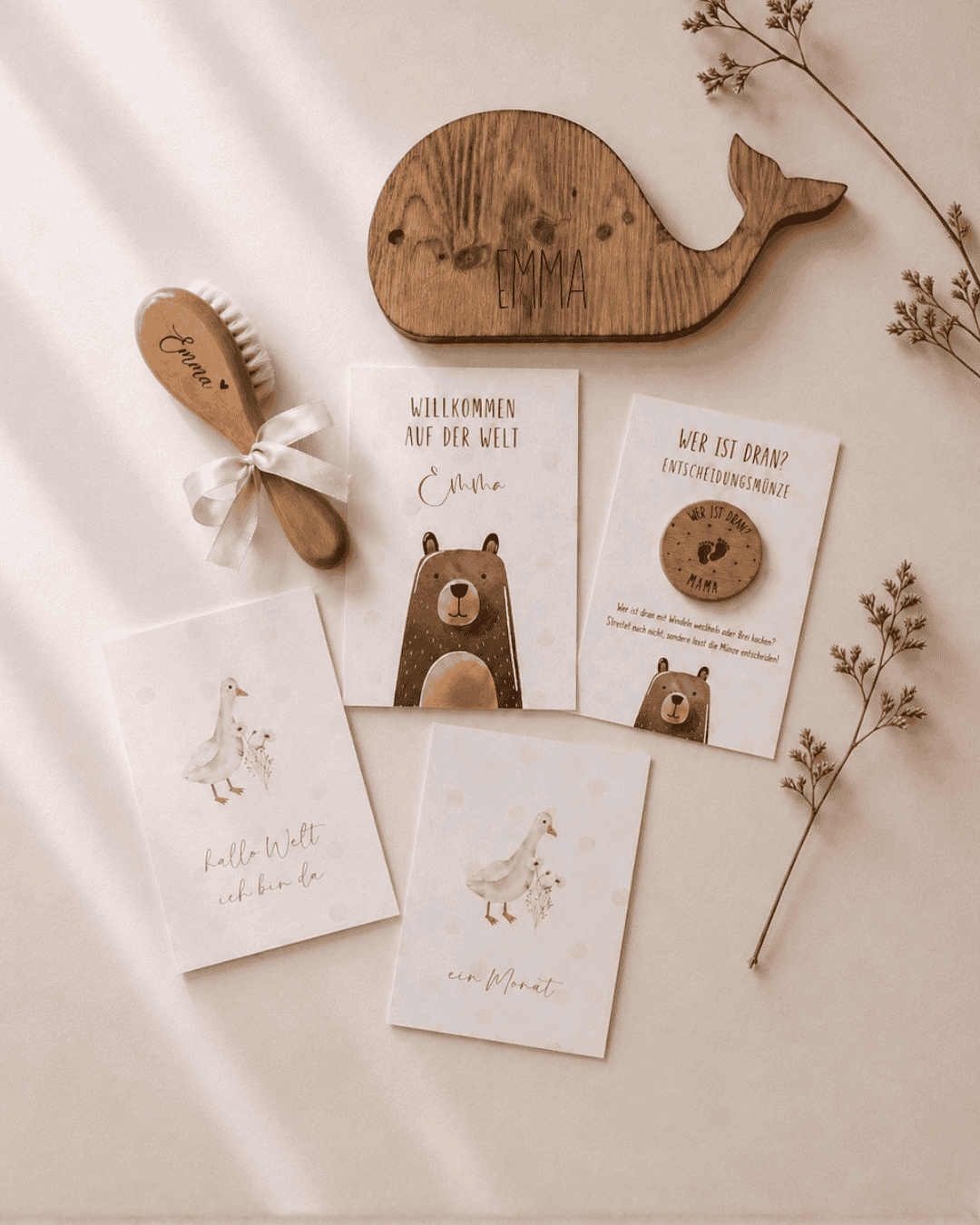 Liebevoll zusammengestelltes Babygeschenk-Set mit personalisierten Produkten auf hellem, minimalistischem Hintergrund: Holz-Wal mit graviertem Namen, weiche Babybürste mit Schleife, personalisierte Willkommenskarte, Entscheidungsmünze für Eltern sowie Meilensteinkarten im sanften Beige-Design – perfekt als individuelles Geschenk zur Geburt oder Babyshower.