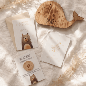 Geschenkset für Babys bestehend aus einer Glückwunschkarte, Meilensteinkarten, Entscheidungsmünze aus Holz und Nachtlicht aus Holz in Form eines Wals in einem ruhigen Untergrund