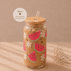 Glas mit Bambusdeckel und Strohhalm, gefüllt mit Eiskaffee, verziert mit sommerlichem Melonen-Design und weißen Blüten, auf hellem Holztisch in warmem, minimalistischem Setting