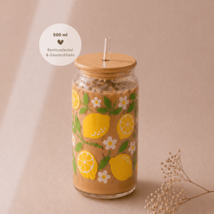 Glas mit Bambusdeckel und Strohhalm, gefüllt mit Eiskaffee, verziert mit sommerlichem Zitronen-Design und weißen Blüten, auf hellem Holztisch in warmem, minimalistischem Setting