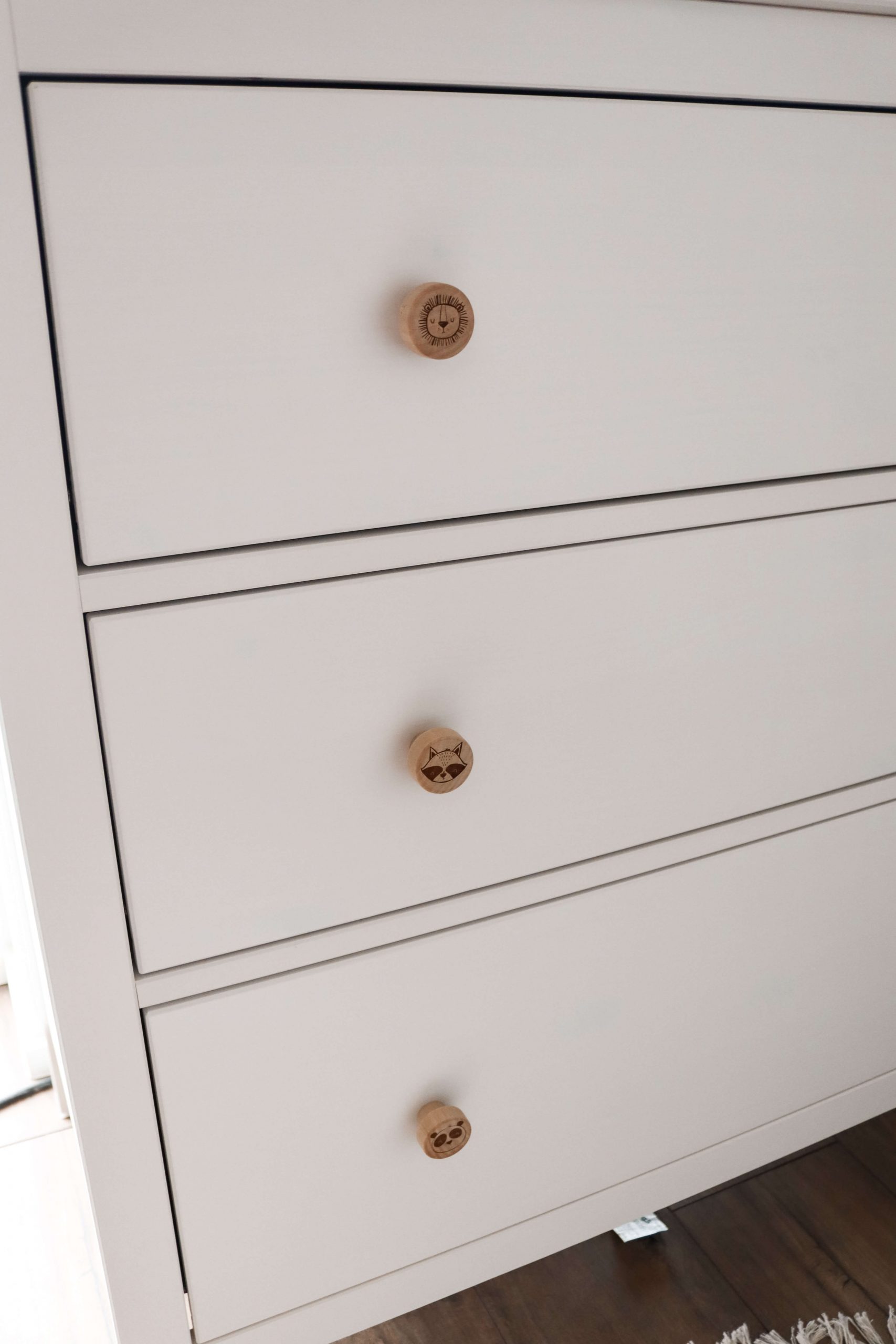Möbelgriff aus hellem Holz mit dem Motiv eines Tigerkopfes. Angebracht an einer Ikea Hemnes Wickelkommode