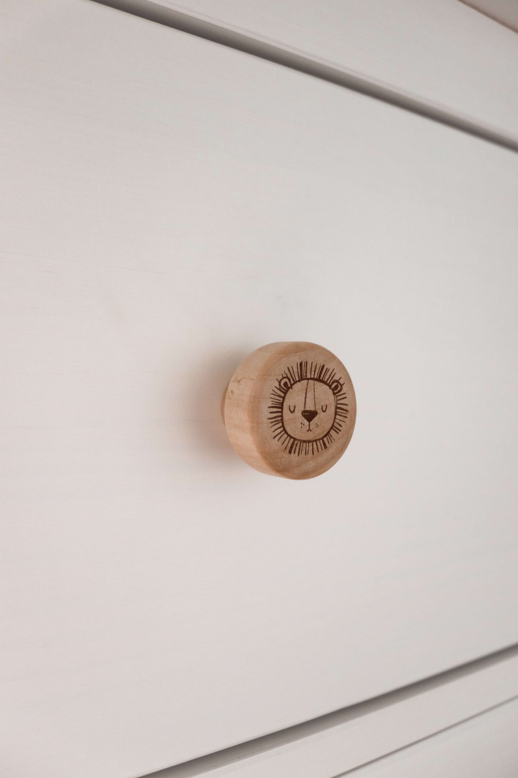 Möbelgriff aus hellem Holz mit dem Motiv eines Tigerkopfes. Angebracht an einer Ikea Hemnes Wickelkommode