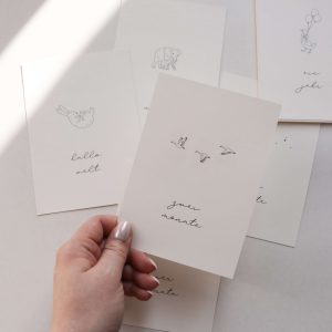 Set von Meilensteinkarten aus Papier mit schlichten Illustrationen und den Monatsbezeichnungen in einem minimalistischen Hintergrund mit natürlichem Sonnenlicht