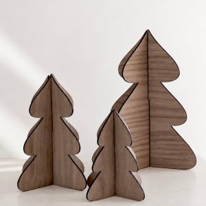 drei Dekotannen aus dunklem Walnussholz in drei verschiedenen Größen nebeneinanderstehend in minimalistischem Hintergrund