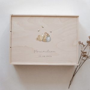 Minimalistische Aufnahme einer hellen Erinnerungskiste mit Bärenmotiv und Bienen aufgedruckt